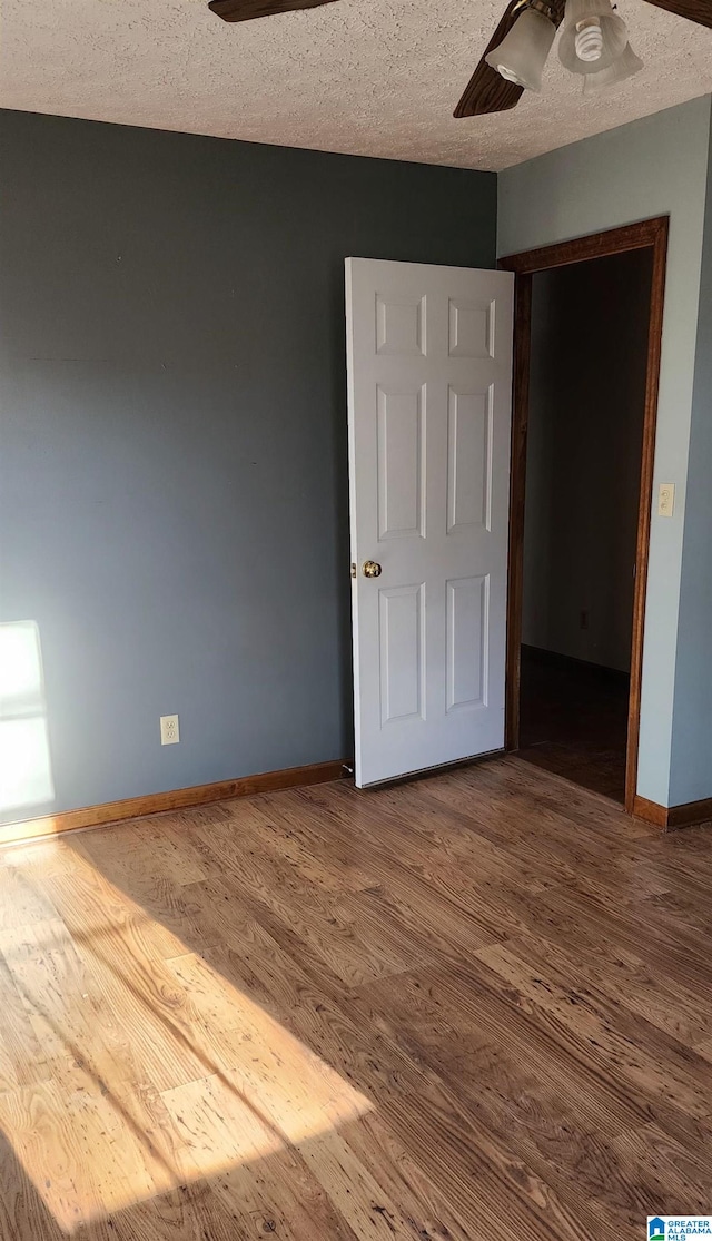 unfurnished bedroom with a closet, ceiling fan, hardwood / wood-style floors, and a textured ceiling