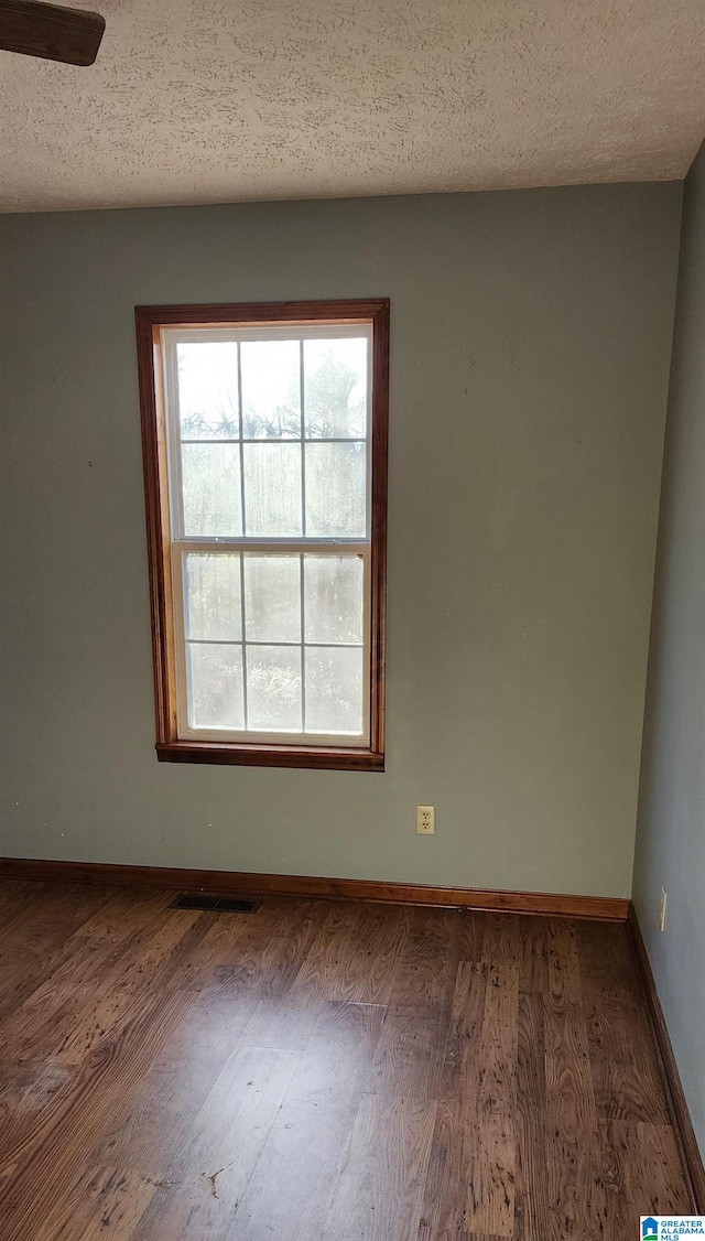 empty room with dark hardwood / wood-style flooring and a textured ceiling