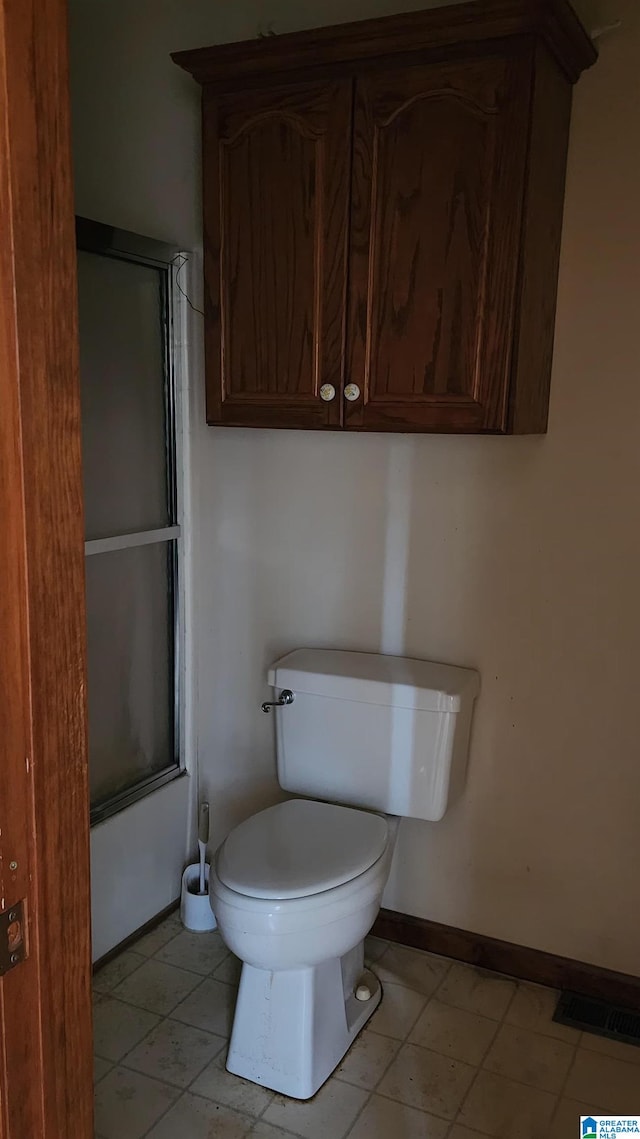 bathroom featuring bath / shower combo with glass door and toilet