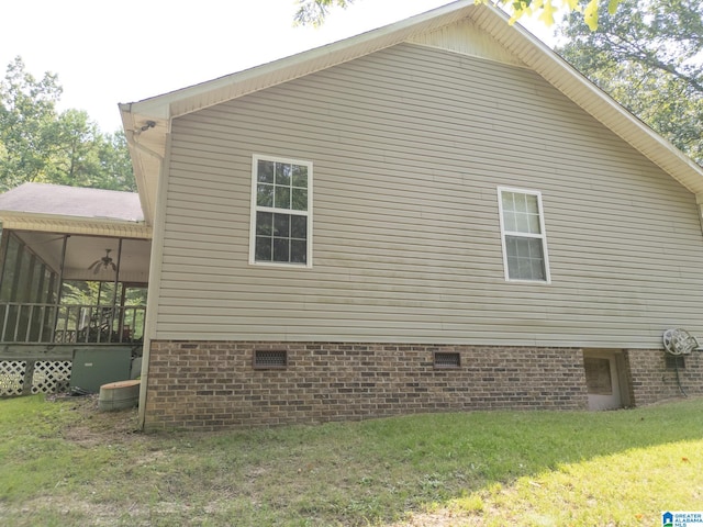 view of side of property featuring ceiling fan, a lawn, and a sunroom