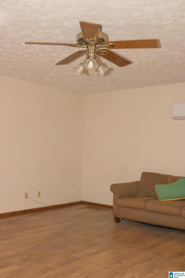 unfurnished living room featuring hardwood / wood-style floors, a textured ceiling, a wall unit AC, and ceiling fan