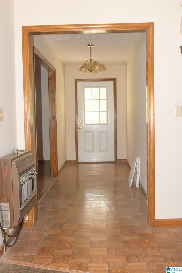 doorway to outside featuring heating unit, dark parquet floors, and an inviting chandelier