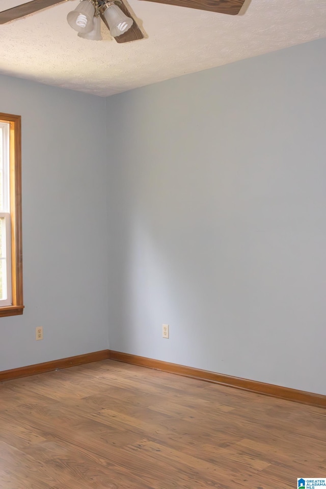 empty room featuring hardwood / wood-style flooring, plenty of natural light, ceiling fan, and a textured ceiling