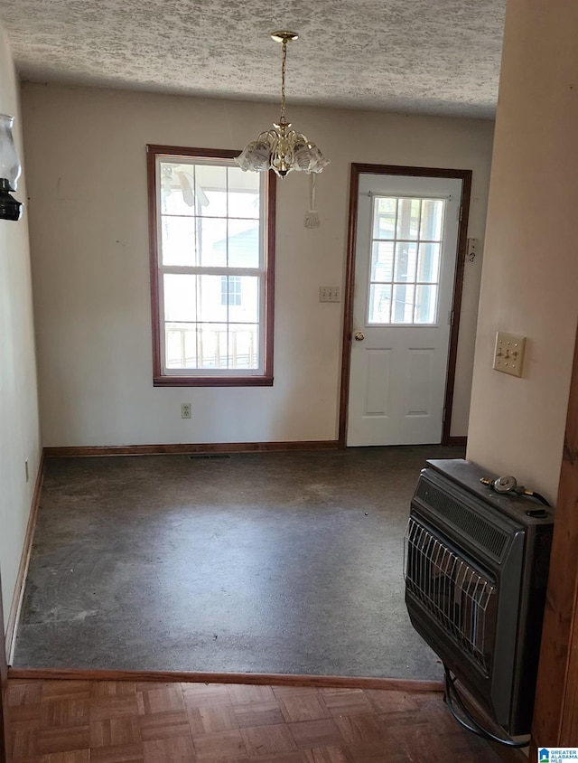 doorway to outside with a wood stove, heating unit, a healthy amount of sunlight, and an inviting chandelier