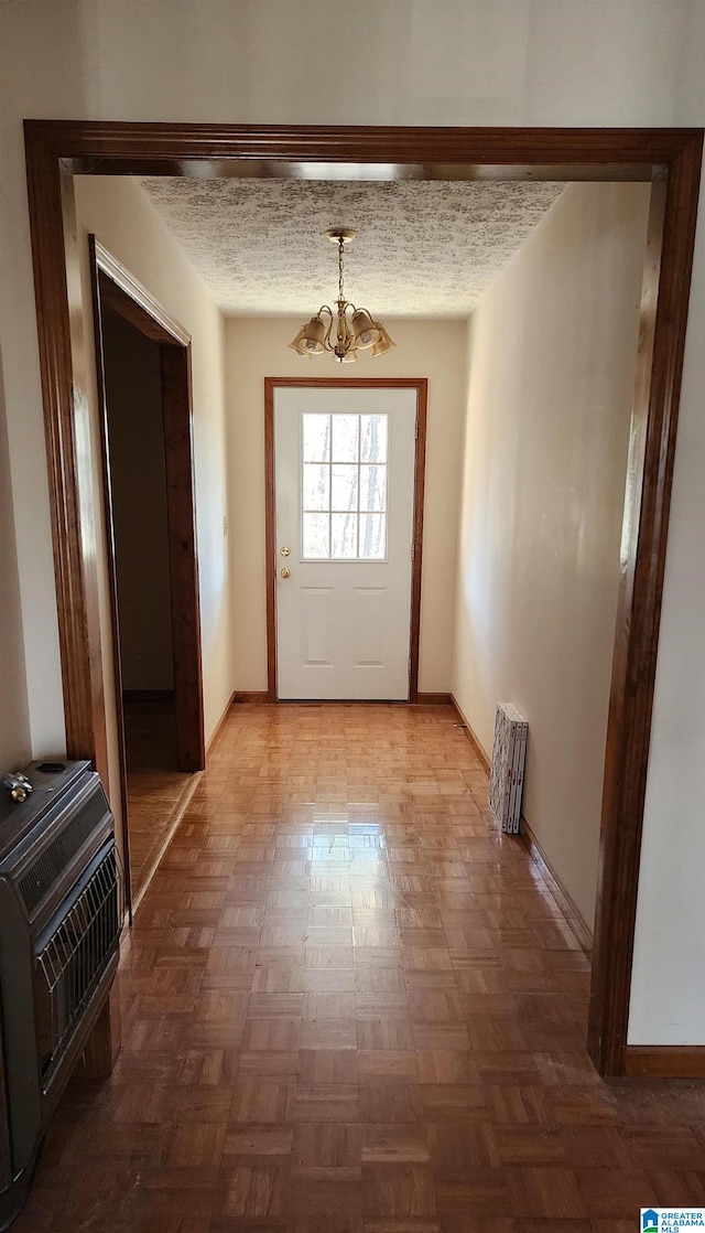 doorway featuring a textured ceiling, heating unit, parquet floors, and a notable chandelier