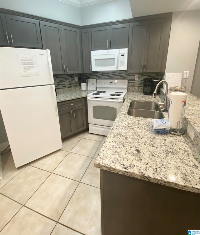 kitchen with light stone counters, white appliances, backsplash, light tile floors, and sink