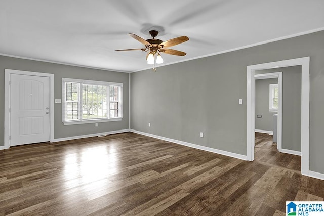 empty room featuring a wealth of natural light, dark wood-type flooring, and ceiling fan