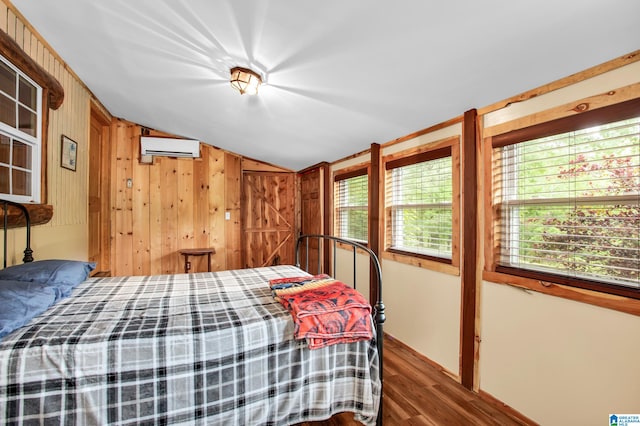 bedroom featuring vaulted ceiling, wood walls, hardwood / wood-style flooring, and an AC wall unit