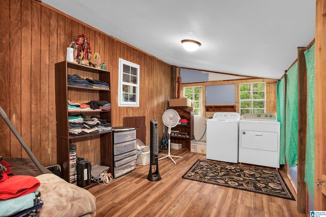 clothes washing area with light hardwood / wood-style flooring, wood walls, and washing machine and dryer