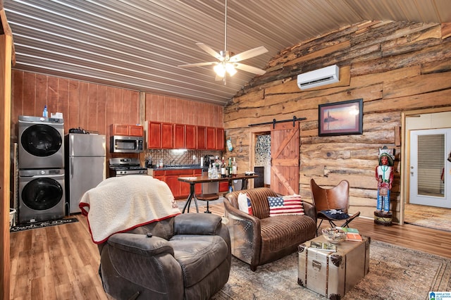 living room featuring ceiling fan, stacked washer / dryer, a barn door, an AC wall unit, and wood-type flooring