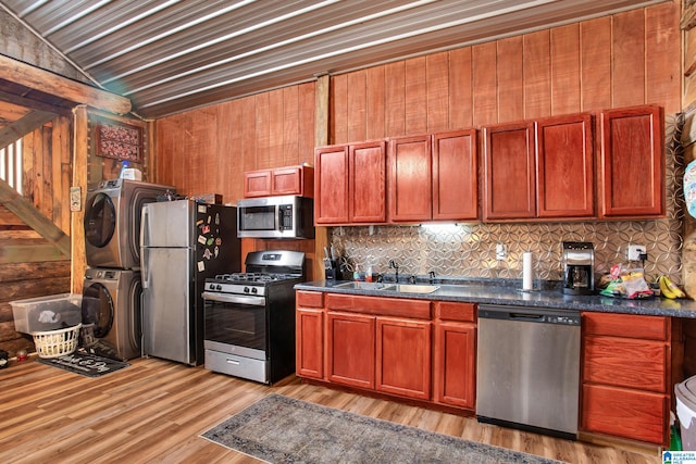 kitchen with stacked washer and clothes dryer, sink, tasteful backsplash, lofted ceiling, and stainless steel appliances