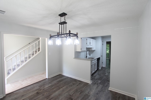 unfurnished dining area with a textured ceiling, sink, dark tile flooring, and a chandelier