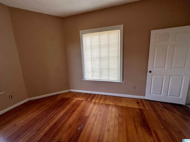 unfurnished room featuring hardwood / wood-style flooring and a textured ceiling