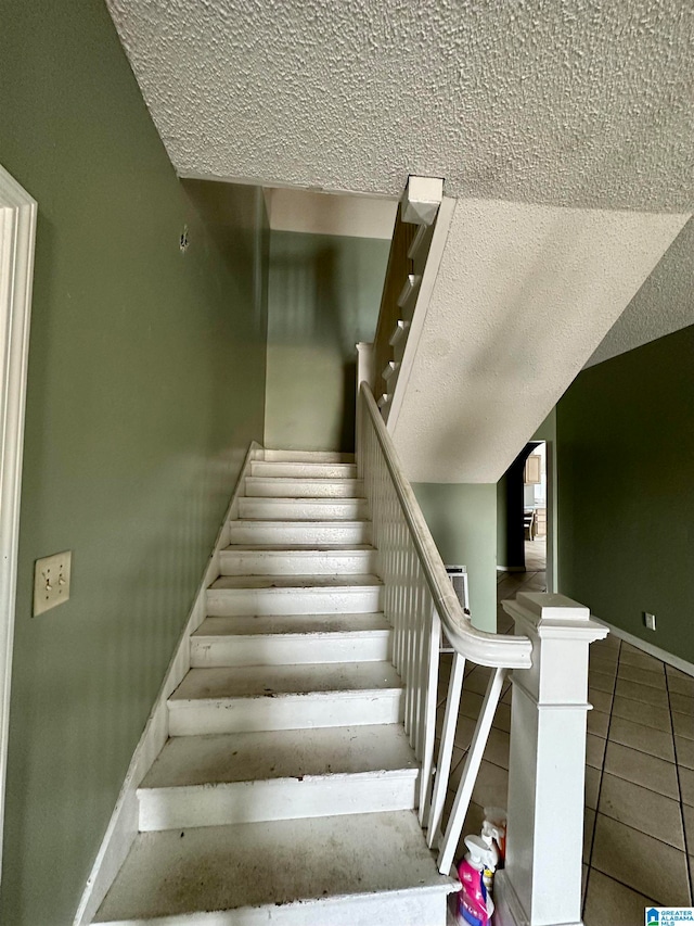 staircase featuring a textured ceiling and tile floors