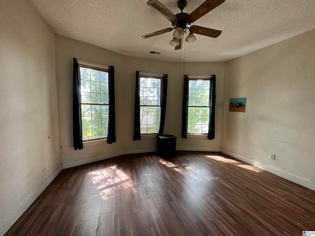 spare room featuring dark hardwood / wood-style flooring, ceiling fan, and a textured ceiling