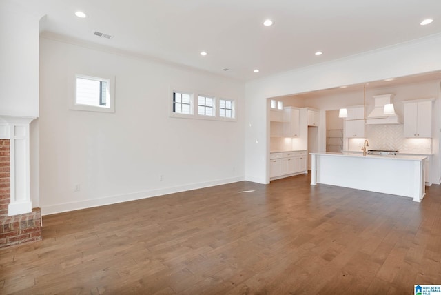 unfurnished living room featuring ornamental molding, a brick fireplace, and dark hardwood / wood-style floors