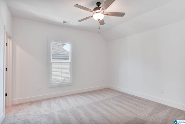 empty room featuring vaulted ceiling, light colored carpet, and ceiling fan