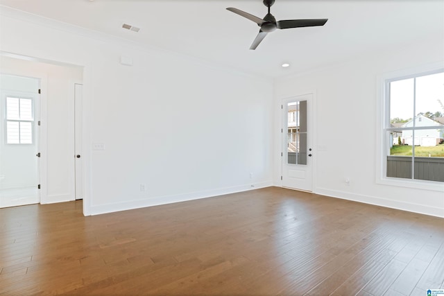 unfurnished living room with ornamental molding, dark wood-type flooring, visible vents, and plenty of natural light