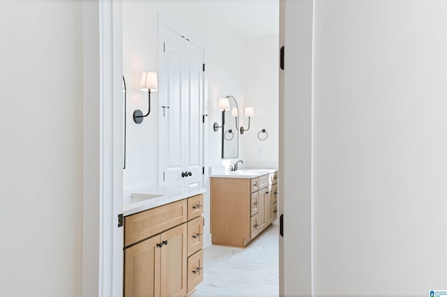 bathroom with two vanities, marble finish floor, and a sink