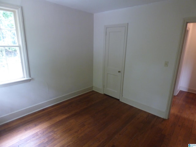 unfurnished bedroom featuring dark hardwood / wood-style flooring and multiple windows