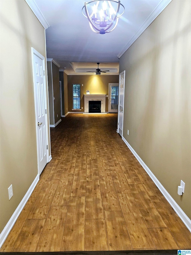 unfurnished living room with ceiling fan with notable chandelier, ornamental molding, and wood-type flooring