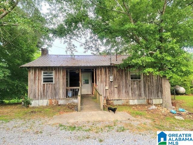 view of front of property with crawl space, covered porch, metal roof, and a chimney