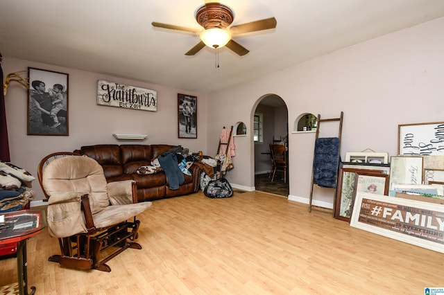 living room with arched walkways, wood finished floors, a ceiling fan, and baseboards