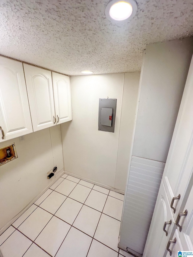 laundry room with light tile patterned flooring, a textured ceiling, electric panel, hookup for a washing machine, and cabinets