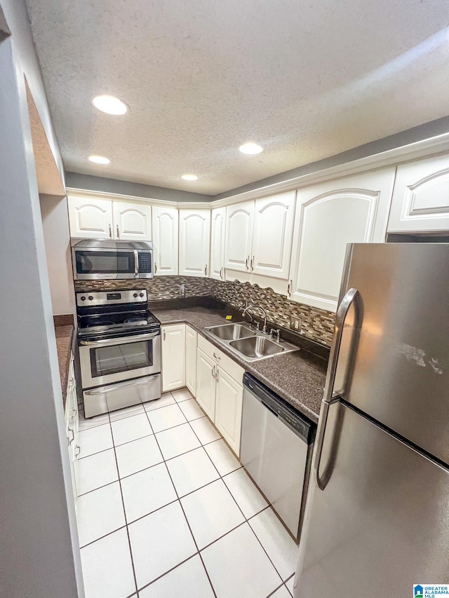 kitchen with appliances with stainless steel finishes, light tile patterned floors, tasteful backsplash, and sink