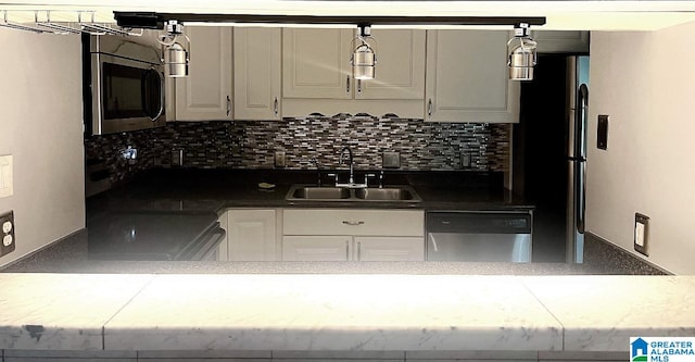 kitchen featuring tasteful backsplash, white cabinets, stainless steel appliances, hanging light fixtures, and sink