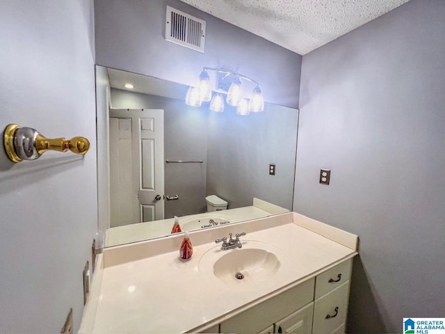 bathroom with toilet, vanity, and a textured ceiling