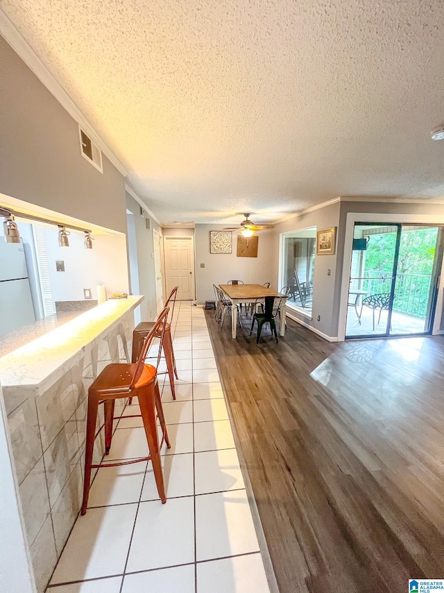 interior space with ceiling fan, crown molding, a textured ceiling, and light hardwood / wood-style flooring