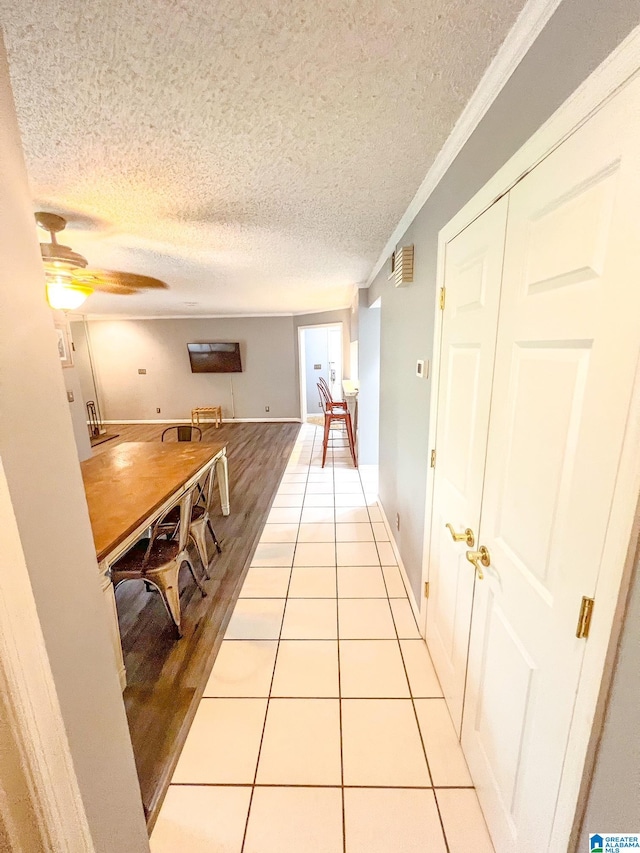 hallway with crown molding, light hardwood / wood-style flooring, and a textured ceiling