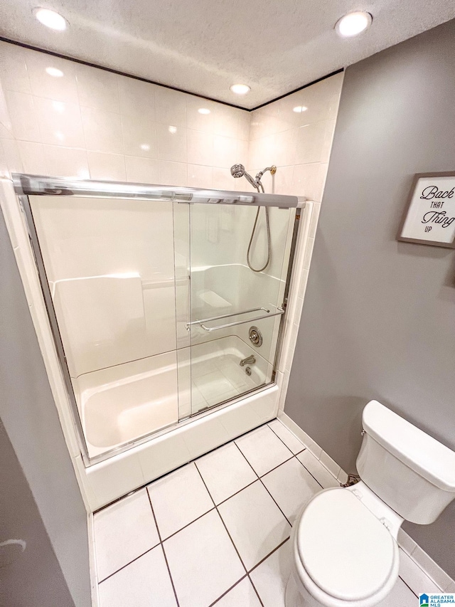 bathroom featuring tile patterned flooring, combined bath / shower with glass door, toilet, and a textured ceiling