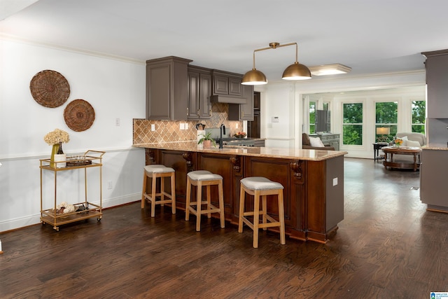 kitchen with light stone countertops, kitchen peninsula, dark hardwood / wood-style flooring, backsplash, and a kitchen bar