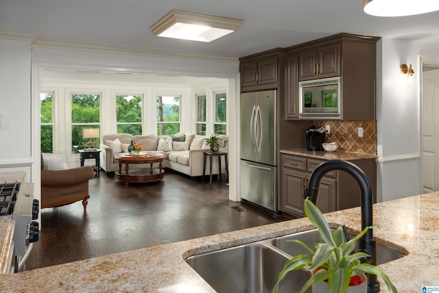 kitchen with light stone counters, dark hardwood / wood-style floors, stainless steel appliances, crown molding, and sink