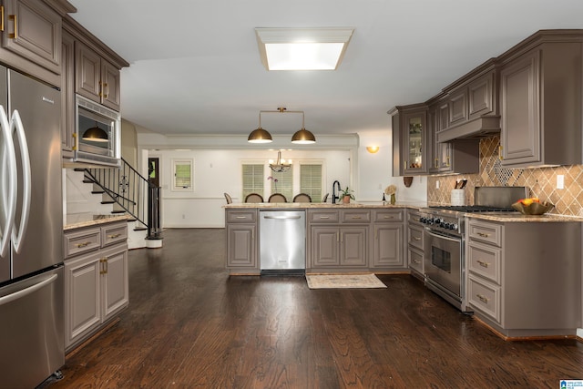 kitchen featuring light stone counters, dark hardwood / wood-style floors, stainless steel appliances, tasteful backsplash, and pendant lighting