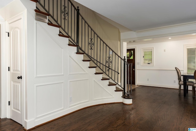 stairs with crown molding and dark wood-type flooring