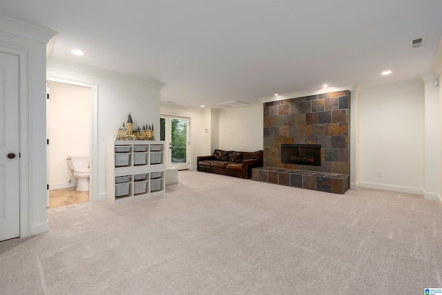 living room with ornamental molding, a tiled fireplace, and carpet floors