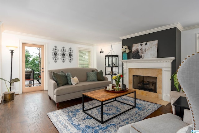 living room featuring crown molding, a tiled fireplace, and hardwood / wood-style floors