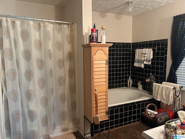 bathroom featuring a textured ceiling and tiled tub