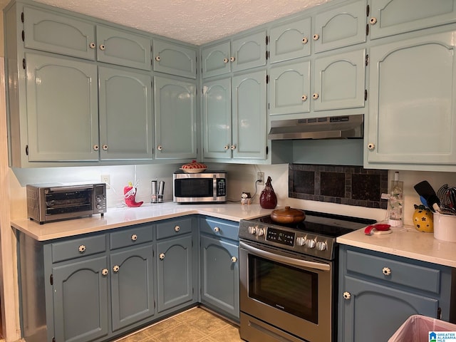 kitchen with a textured ceiling, stainless steel appliances, gray cabinets, extractor fan, and tasteful backsplash