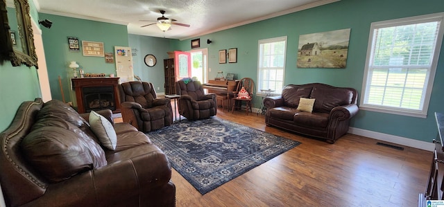 living room with ceiling fan, plenty of natural light, ornamental molding, and hardwood / wood-style flooring