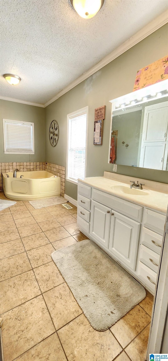 bathroom featuring crown molding, tile flooring, a washtub, vanity, and a textured ceiling