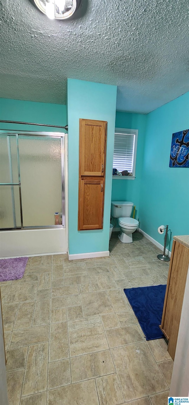 bathroom with a textured ceiling, tile flooring, and toilet