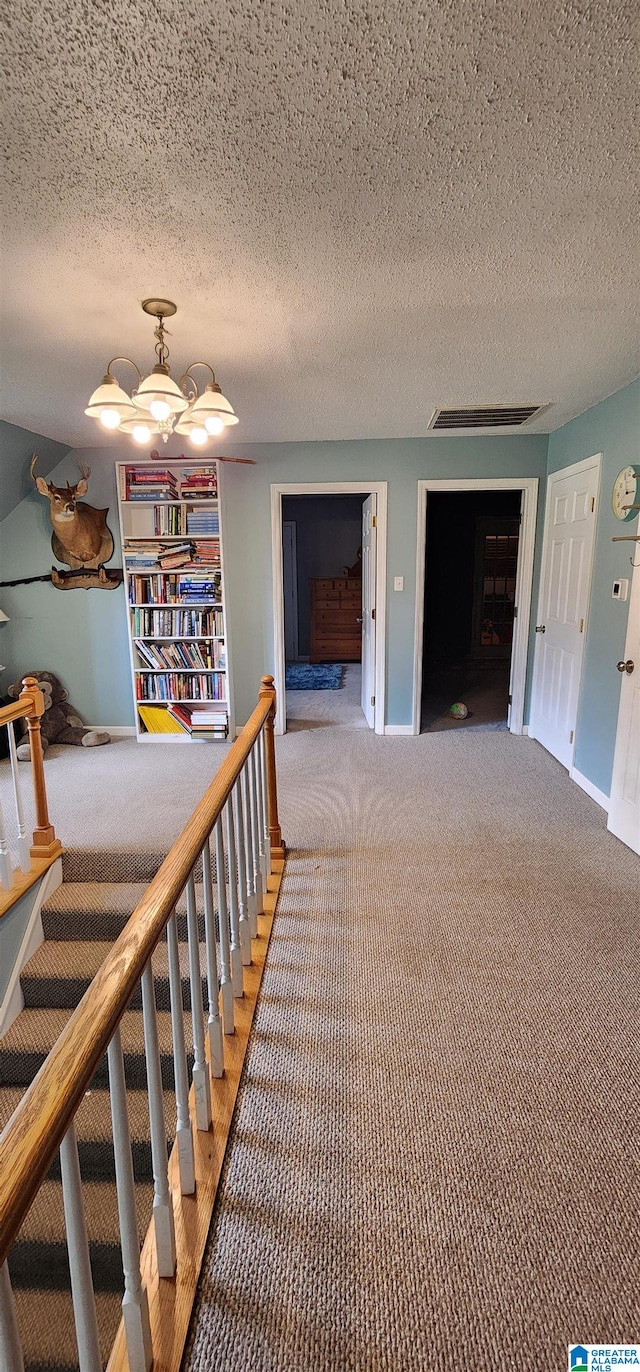 staircase featuring built in features, carpet floors, and a textured ceiling