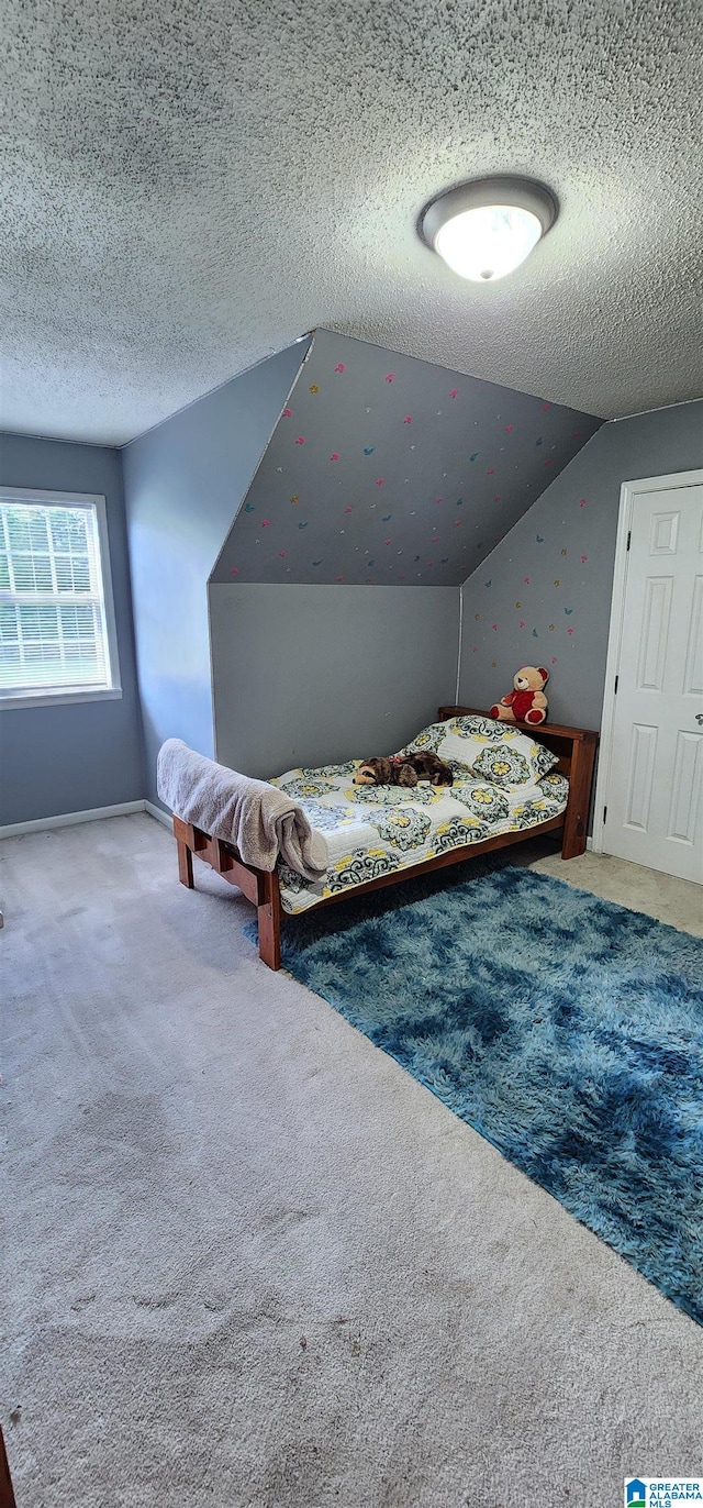 unfurnished bedroom with carpet floors, a textured ceiling, and lofted ceiling