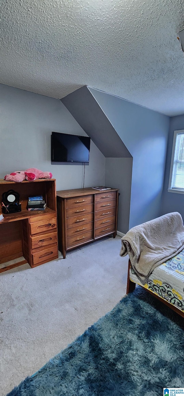 carpeted bedroom with a textured ceiling and lofted ceiling