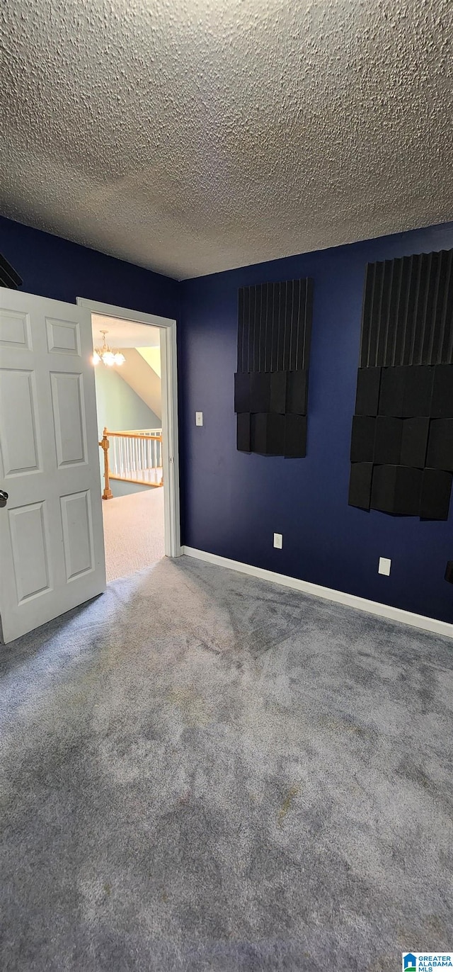 carpeted spare room with an inviting chandelier and a textured ceiling