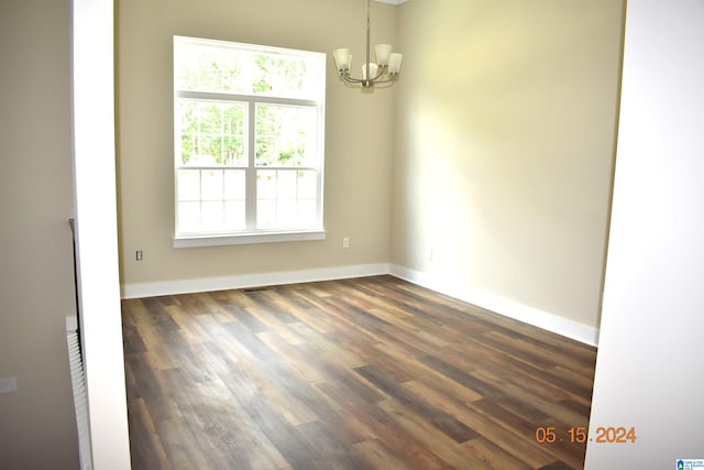 spare room with an inviting chandelier and dark wood-type flooring